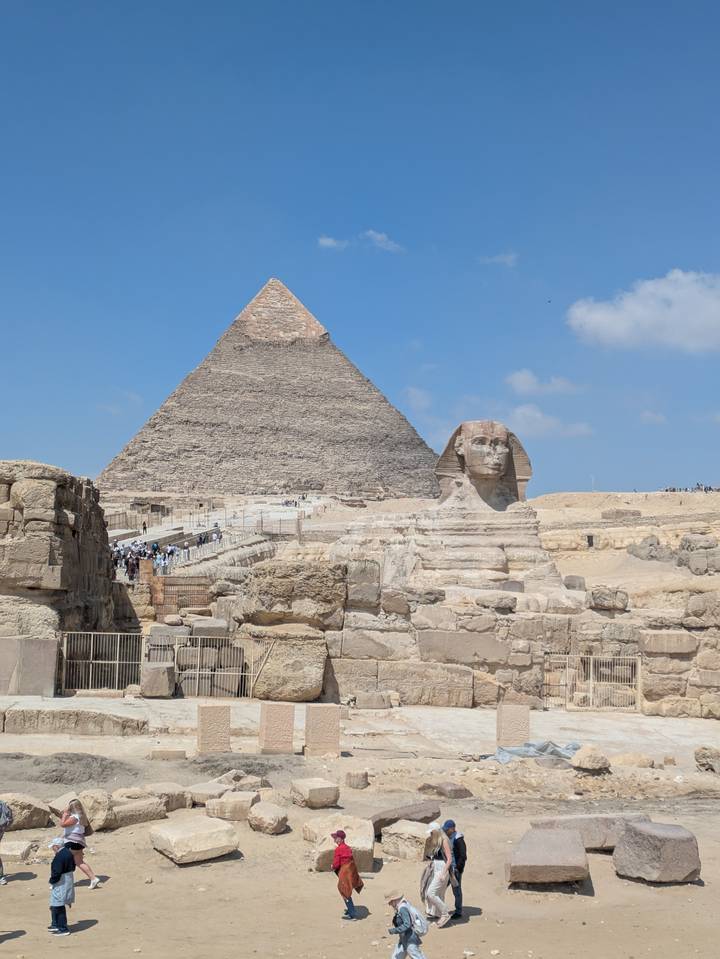 Iconic view of the Sphinx with the Great Pyramid of Giza rising behind under a clear blue sky.