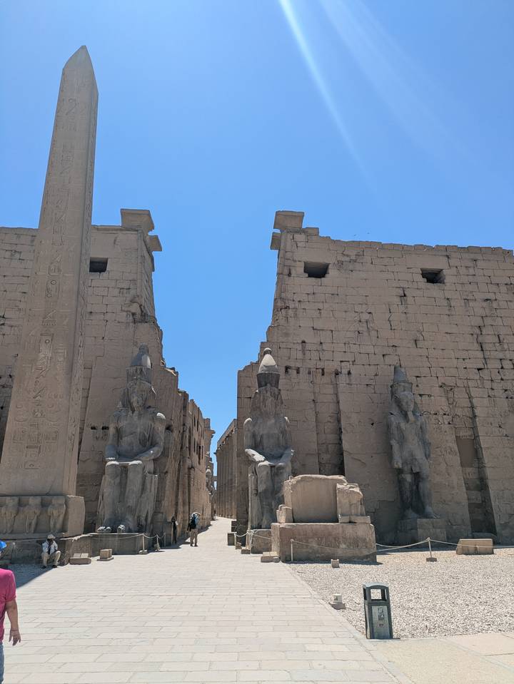 Statues of seated pharaohs and an obelisk flank the monumental entrance of Luxor Temple.