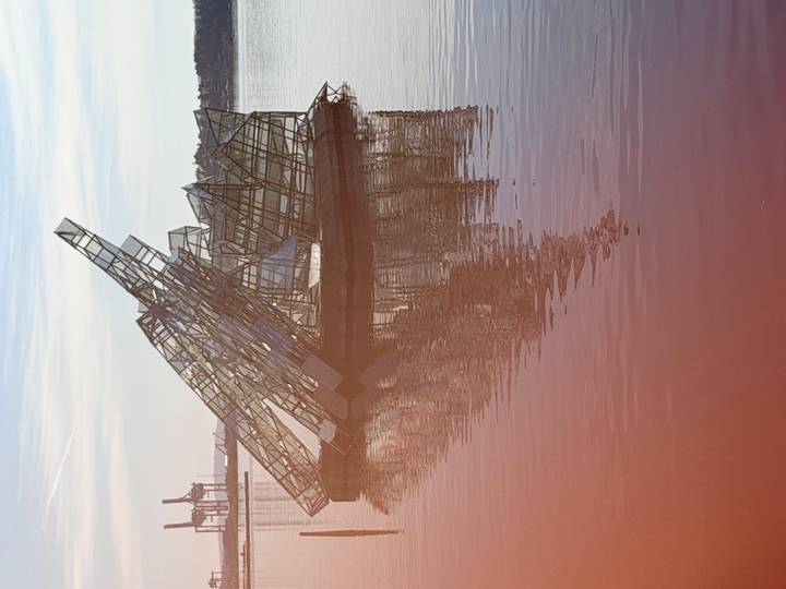 Modern glass sculpture resembling broken icebergs floating on calm water with soft morning light.