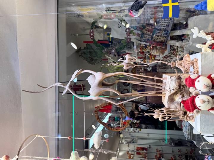 Shop-window display of delicate carved wooden reindeer surrounded by festive ornaments and souvenirs.
