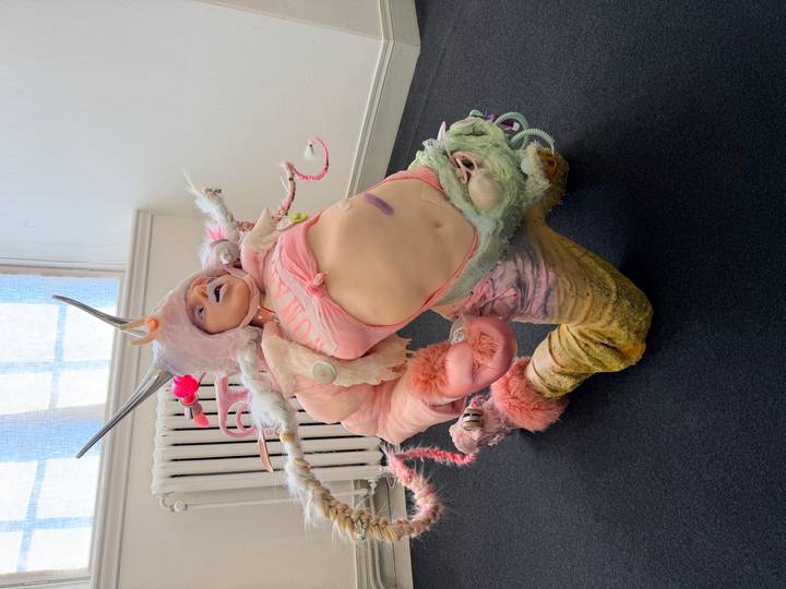 Person wearing an elaborate pastel fantasy costume posed inside a modern gallery space
