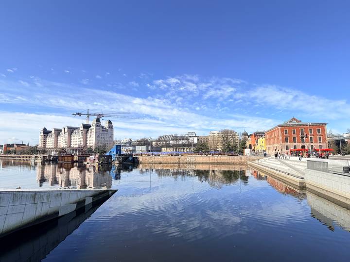 Panoramic view of Oslo harbor with modern buildings, cranes and crisp reflections on the water