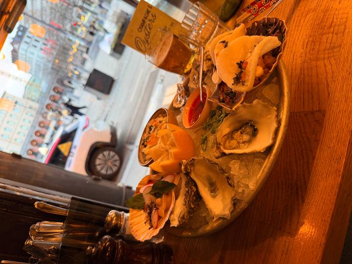Platter of fresh oysters and assorted seafood with beer on a wooden table inside a bistro