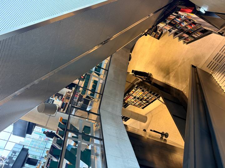 Multi-level modern library interior with escalators, bookshelves and large windows