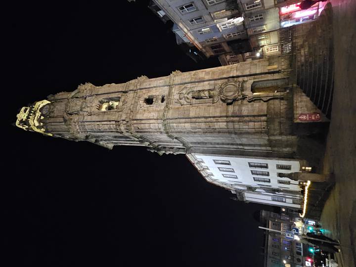 Nighttime view of Porto’s stone Clérigos Tower dramatically lit against a dark sky.