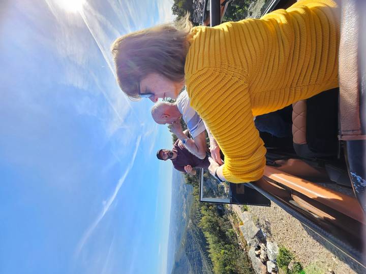 Travellers enjoy an open-top jeep ride on a sunny hilltop with wide valley views.