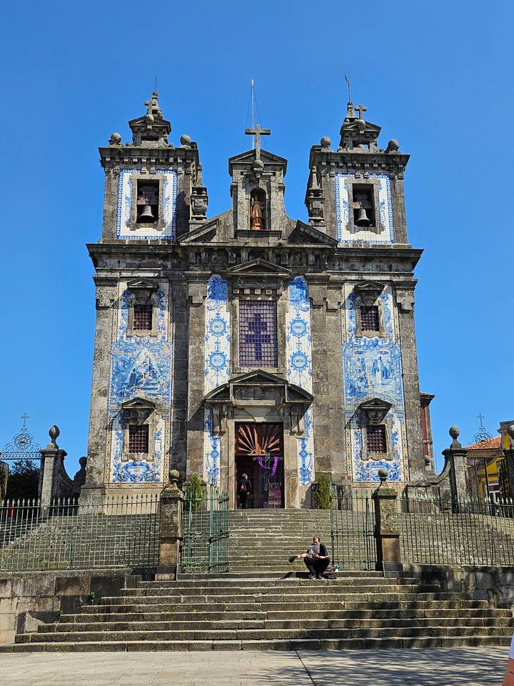 Ornate church façade decorated with classic blue-and-white azulejo tiles under a clear sky.