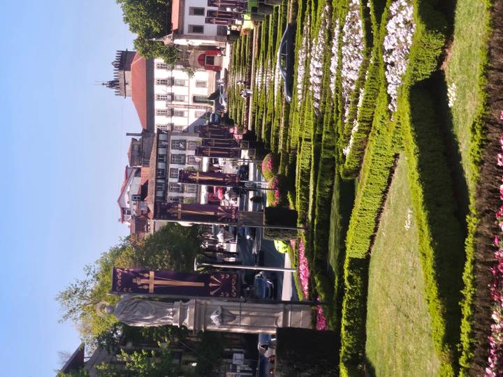 Manicured terraced flower gardens lined with purple Easter banners in a historic town square.