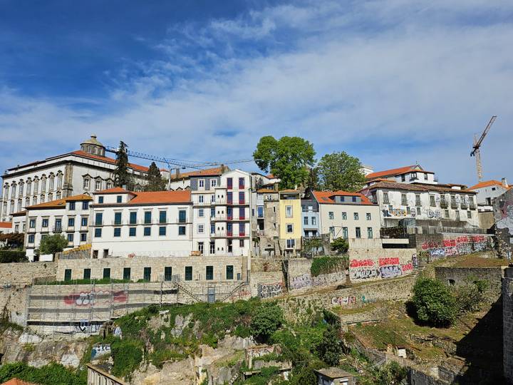 Graffiti-covered retaining walls below colourful hillside homes in Porto.