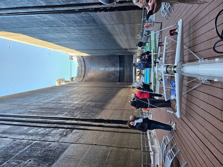 Cruise passengers stand on deck while their ship is lowered inside a massive river lock chamber.