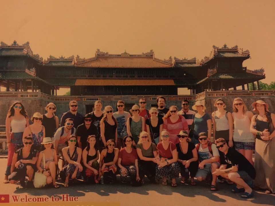 Groupe de personnes posant devant un grand bâtiment historique.