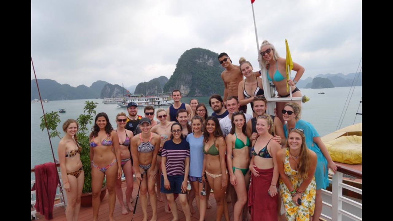Groupe de personnes posant sur un bateau avec une vue sur des karsts calcaires en arrière-plan.