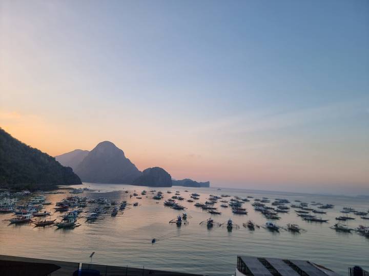 Wide harbour panorama at pastel dusk with countless boats and a dark karst skyline.