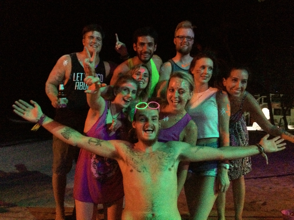 Group of people posing at night with bright paint and clothes.