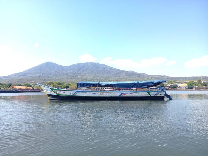 Wooden cargo boat moored on calm water with a volcanic mountain backdrop