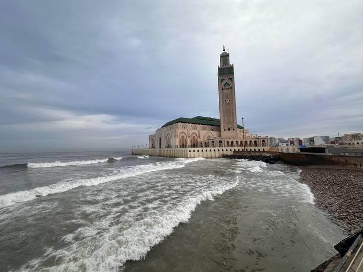 Hassan II Mosque standing over crashing Atlantic waves under an overcast sky