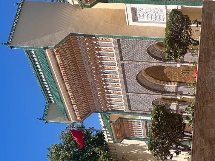 Ornate green-tiled gate of the Royal Palace in Fes under clear blue sky