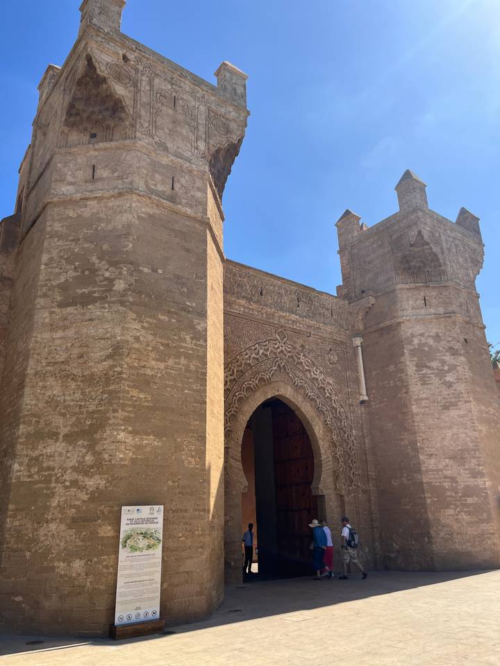 Historic stone gateway and fortified walls under a clear blue sky in Morocco.