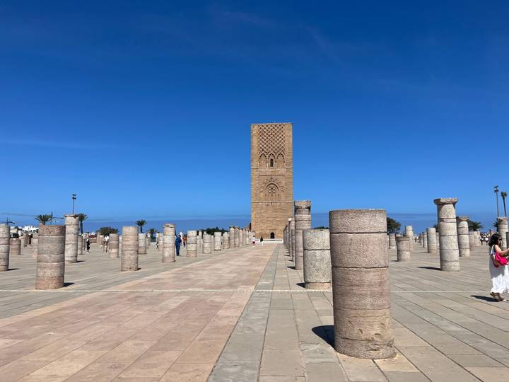 The Hassan Tower rises among rows of ancient stone columns on a bright day.