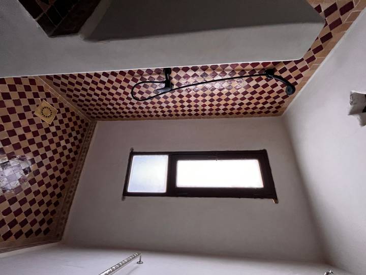Simple tiled bathroom with Moroccan-style shower alcove and small window