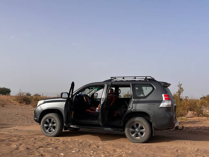 4x4 vehicle with doors open parked on dusty desert plain under hazy sky