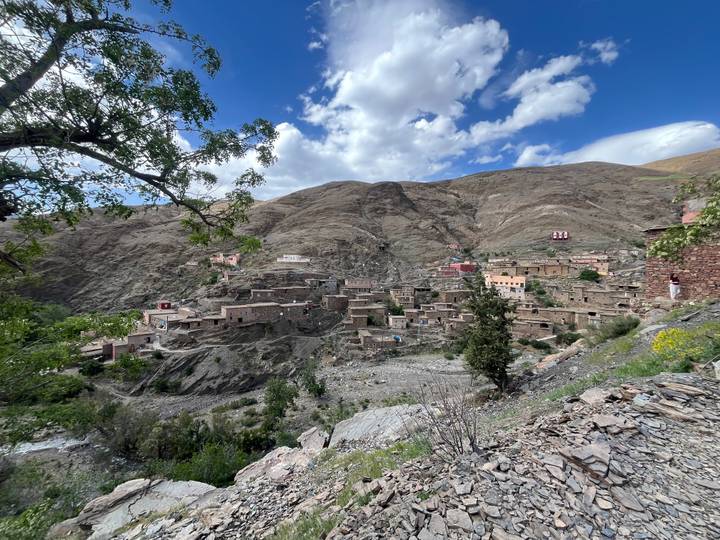 High Atlas mountain village built into steep rocky slopes under scattered clouds