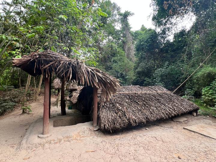 Thatched camouflage hut in dense jungle setting at the historic Cu Chi tunnels site.