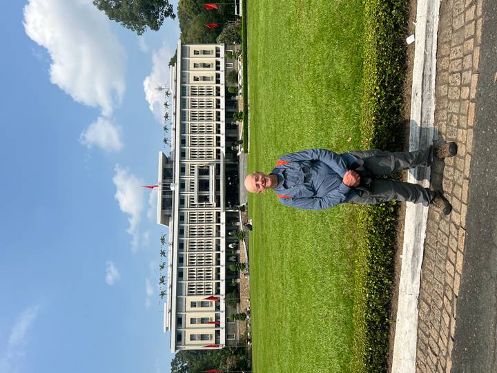 Traveler posing on the lawn before the façade of the Reunification Palace under a blue sky.
