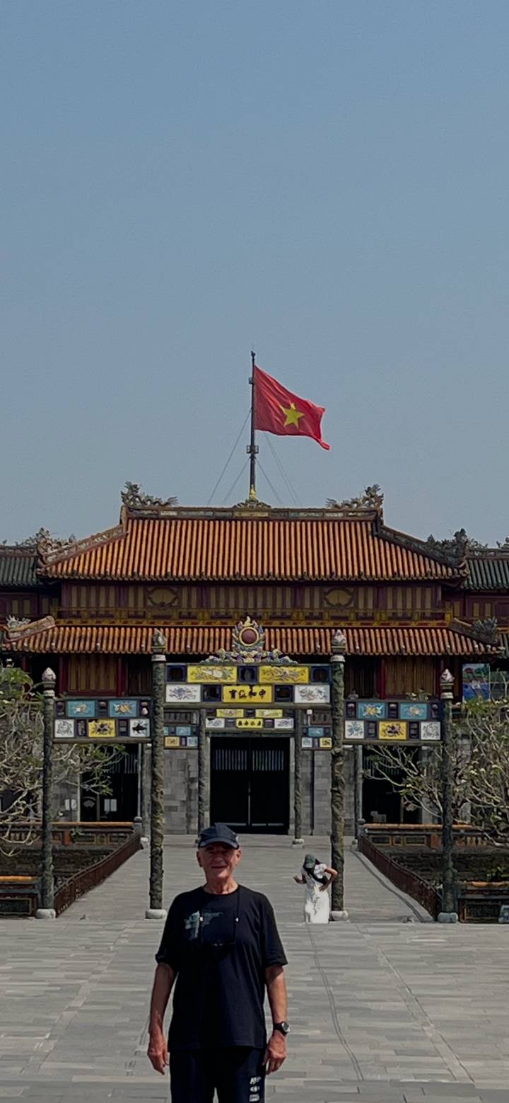 Close-up of a Vietnamese flag flying above an ornate imperial roofline.