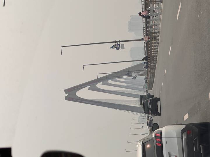 Vehicles crossing the modern cable-stayed Nhat Tan Bridge under hazy skies.