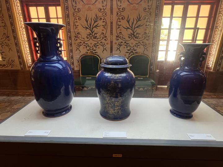 Display case with three deep blue porcelain vases in a palace museum.