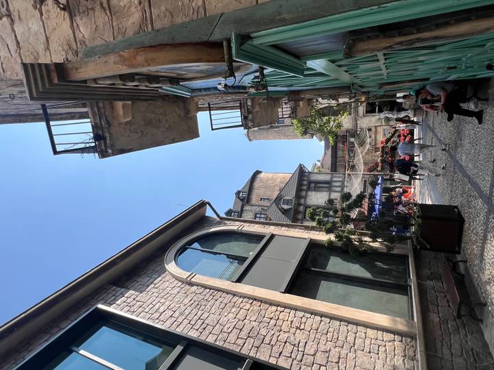 Narrow European-style street in Ba Na Hills with tourists strolling under clear skies.