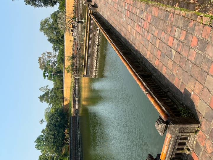 Serene moat corner with tiled walkway and still water inside an old citadel.