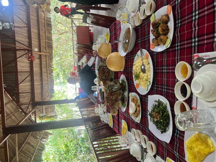 Traditional Vietnamese meal spread on a red-checked tablecloth in an open-air restaurant.