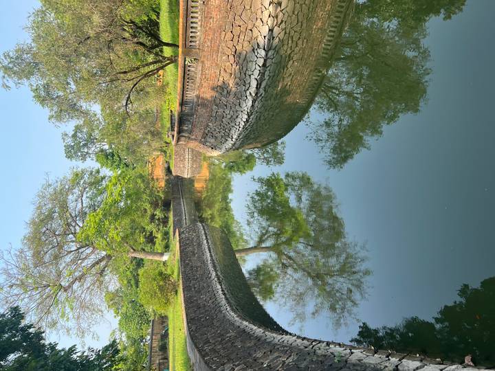 Curving defensive canal bordered by stone walls reflecting surrounding trees.