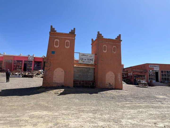 Twin adobe gate towers marking the Col du Tichka mountain pass with small market stalls around