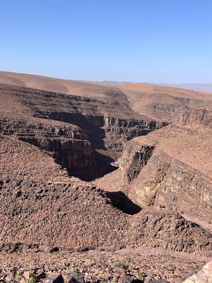 Vast rocky canyon with steep layered cliffs carving through the barren desert landscape.