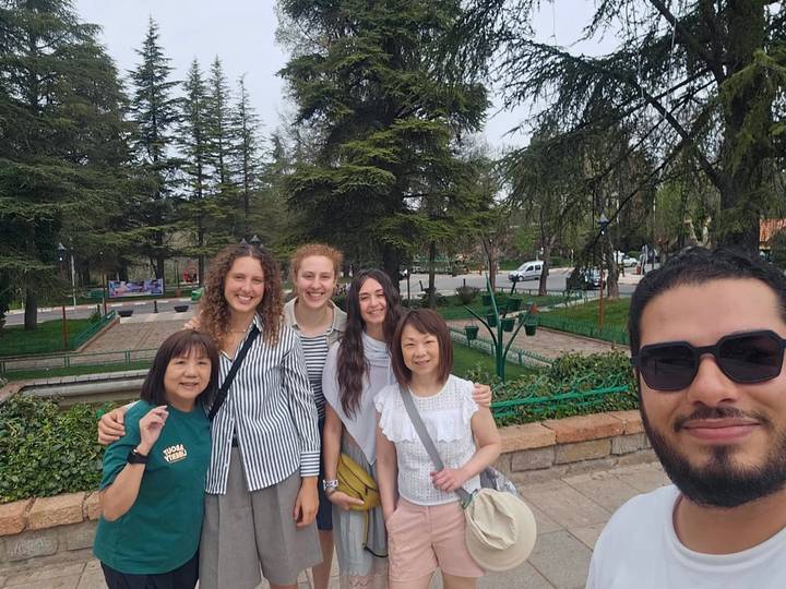 Smiling tour group taking a selfie together in a leafy park