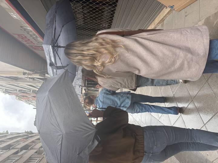 A similar view of women walking with umbrellas between tall apartment blocks.