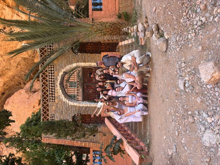 Third angle of the same travel group crouching and standing before a rustic arched doorway.