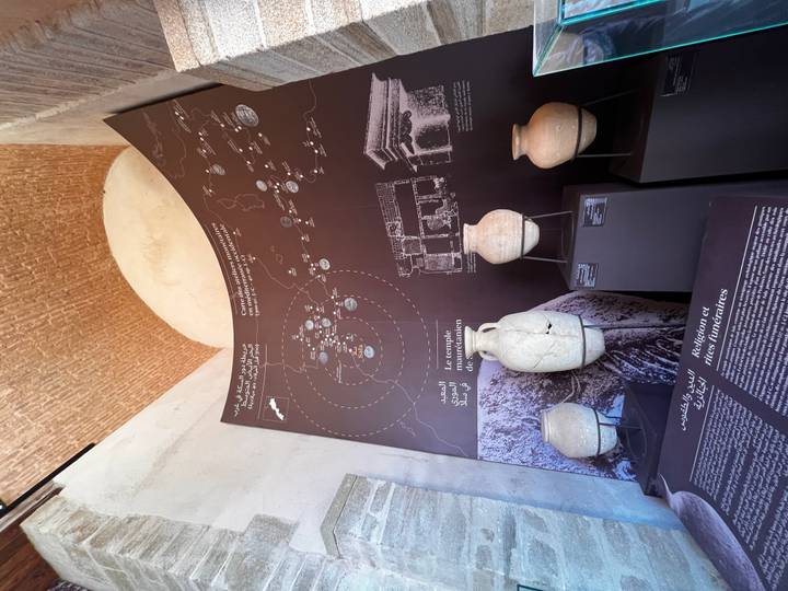 Museum exhibit with map board and ancient pottery jars displayed under vaulted brick ceiling.