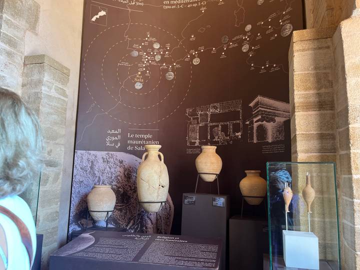 Close look at museum information panel about Sala temple with pottery artefacts in glass cases.