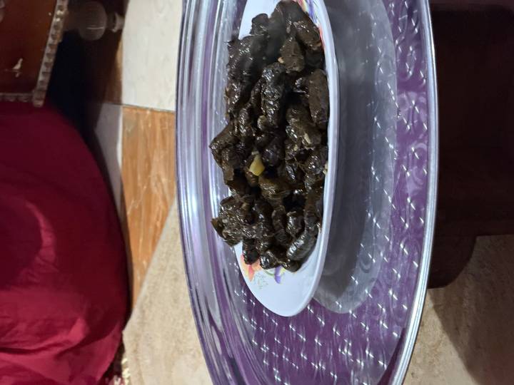 Plate of stuffed grape leaves served on a low round tray inside a local home.