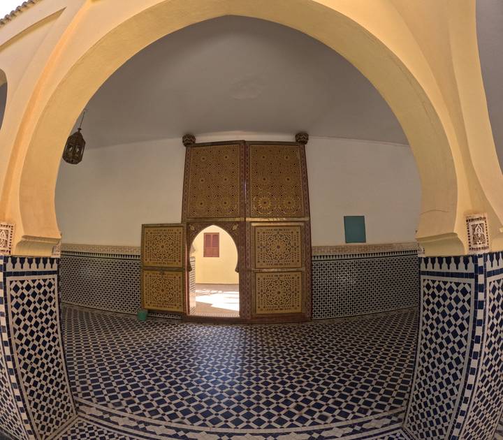 Traditional Moroccan room with ornate wooden doors and blue geometric zellige tilework.