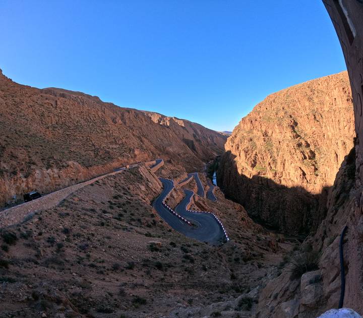 Switchback mountain road winds through steep ochre cliffs of a dramatic gorge at dusk light.