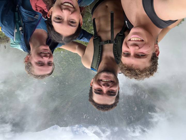 Group of hikers smiling for a selfie amidst misty green mountains on the Inca Trail.