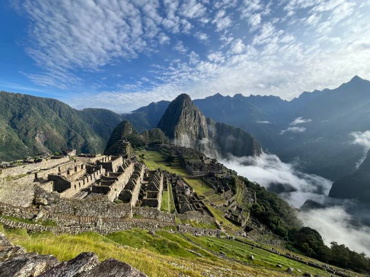 Iconic aerial view of Machu Picchu’s stone terraces rising above clouds and Andean peaks.