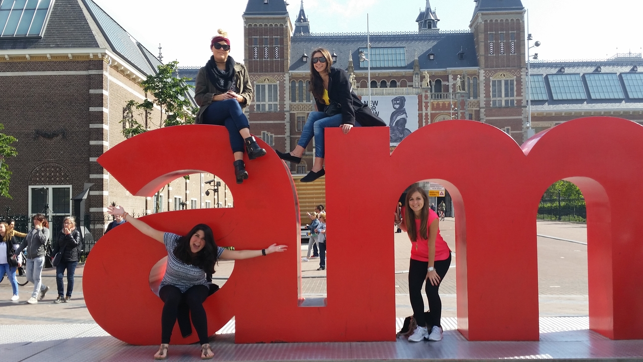 Quatre personnes posant avec de grandes lettres sur une place publique.