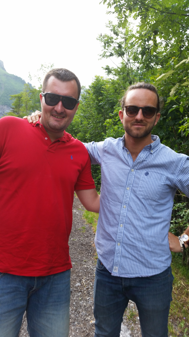 Deux hommes debout dans une zone boisée.