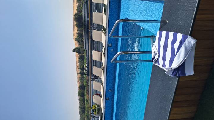 Sun-soaked deck with blue swimming pool and loungers overlooking the Nile’s desert shoreline.